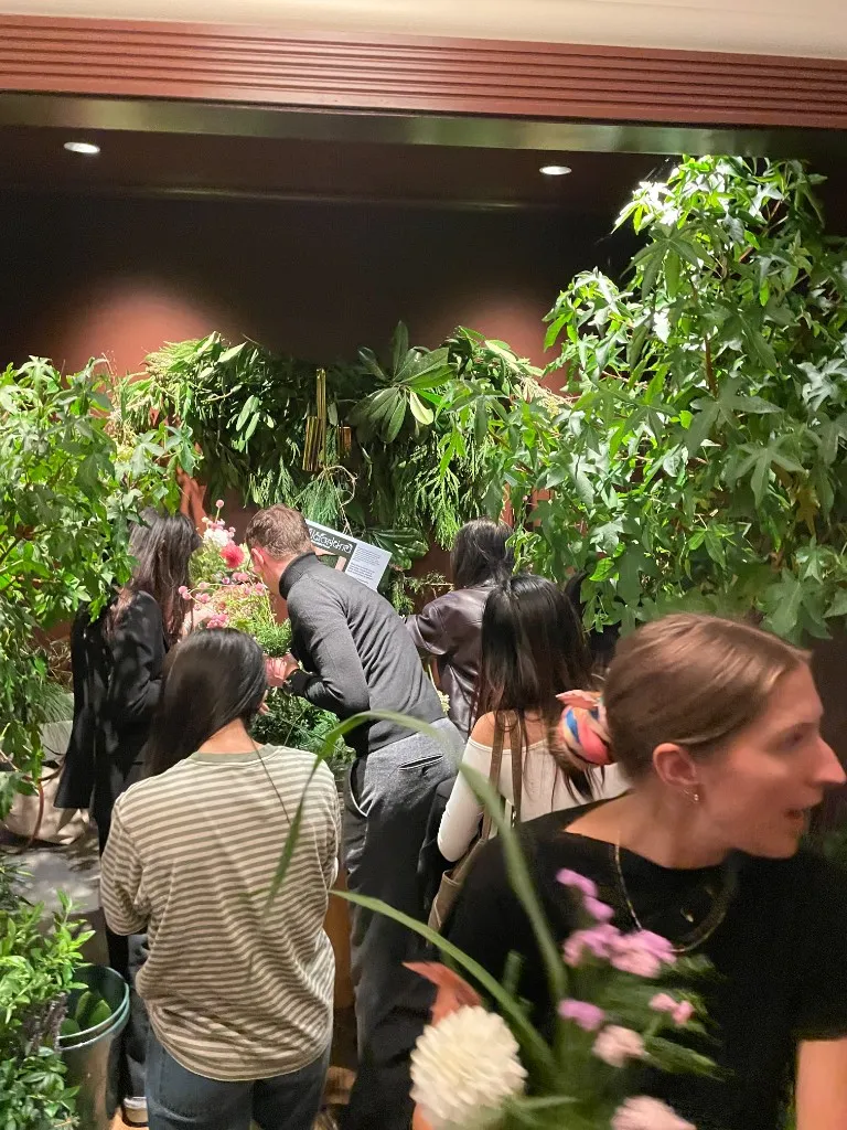 Guests gathered at a living wall of tropical plants and hanging greenery, arranging flowers.